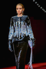 Load image into Gallery viewer, Model wearing a stylish outfit with a dark top and colorful fringe on a red carpet.
